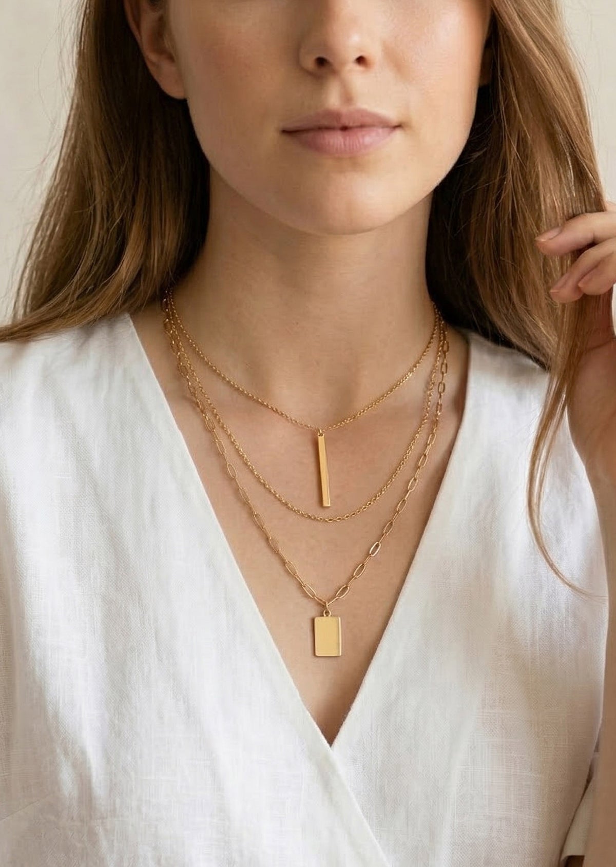 Woman wearing a gold necklace with a white top