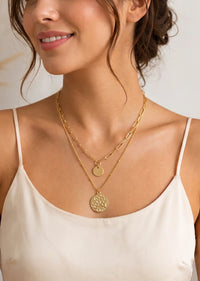 Wearing a modern two-layered necklace in gold dangled with two small charms.