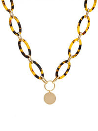 A statement necklace against a white background, featuring large, oval tortoiseshell resin links connected by gold-toned metal and a central, polished gold-toned circular pendant.