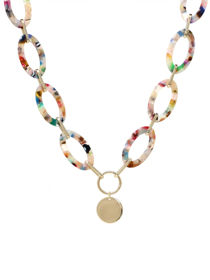 A statement necklace against a white background, featuring large, oval multi colored resin links connected by gold-toned metal and a central, polished gold-toned circular pendant.
