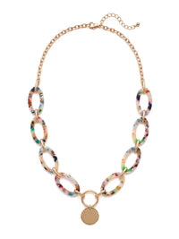 A statement necklace against a white background, featuring large, oval multi colored resin links connected by gold-toned metal and a central, polished gold-toned circular pendant.