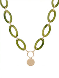 A statement necklace against a white background, featuring large, oval olive green colored resin links connected by gold-toned metal and a central, polished gold-toned circular pendant.