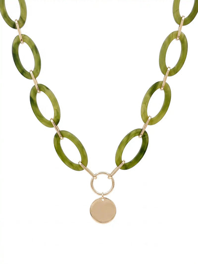 A statement necklace against a white background, featuring large, oval olive green colored resin links connected by gold-toned metal and a central, polished gold-toned circular pendant.