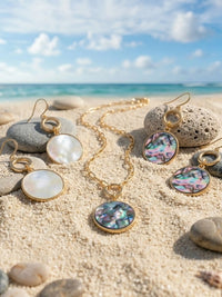 A close-up product image of the Modern Abalone Short Necklace, displaying a round, iridescent abalone shell pendant hanging from a gold-plated paperclip chain against a clean, light background.