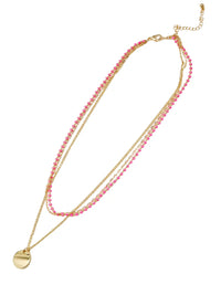 A gold-tone layered necklace featuring two strands of small pink faceted beads and a flat round gold disc pendant, displayed on a clean white background.