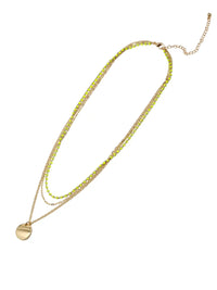 A gold-toned multi-strand necklace featuring lime green faceted beads and a flat circular gold pendant, displayed on a clean white background.