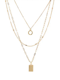 A gold layered necklace set featuring three distinct chain styles: a delicate cable chain with a small ring pendant, a medium cable chain with a rectangular block pendant, and a fine paperclip chain. The necklaces are displayed on a clean white background.