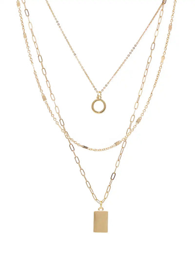 A gold layered necklace set featuring three distinct chain styles: a delicate cable chain with a small ring pendant, a medium cable chain with a rectangular block pendant, and a fine paperclip chain. The necklaces are displayed on a clean white background.