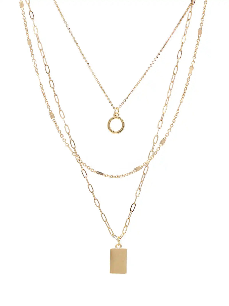 A gold layered necklace set featuring three distinct chain styles: a delicate cable chain with a small ring pendant, a medium cable chain with a rectangular block pendant, and a fine paperclip chain. The necklaces are displayed on a clean white background.