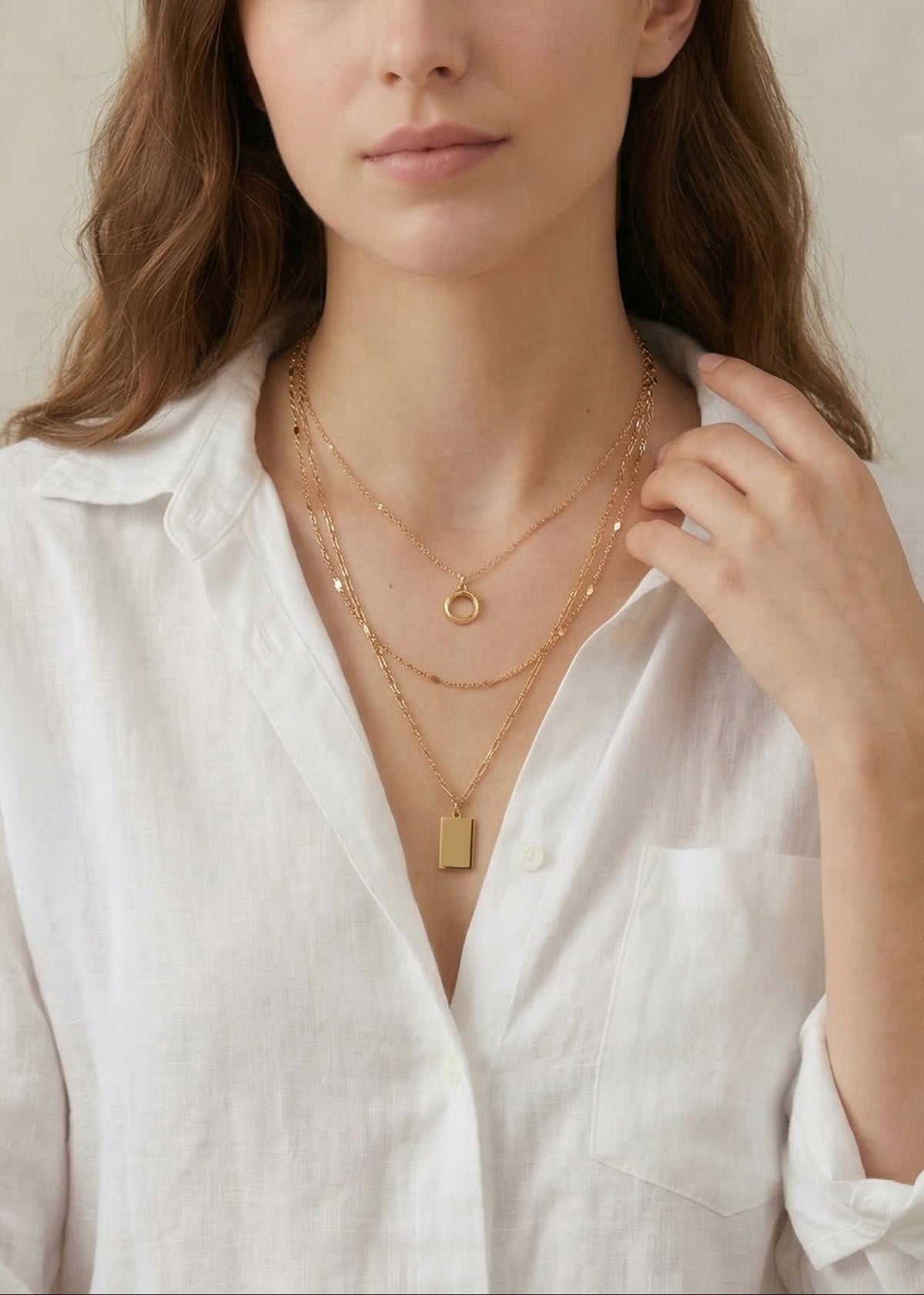 Woman wearing gold necklaces against a neutral background