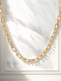 A bold gold link chain necklace with geometric links and polished bead connectors.