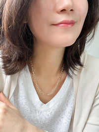 A bold gold link chain necklace with geometric links and polished bead connectors.
