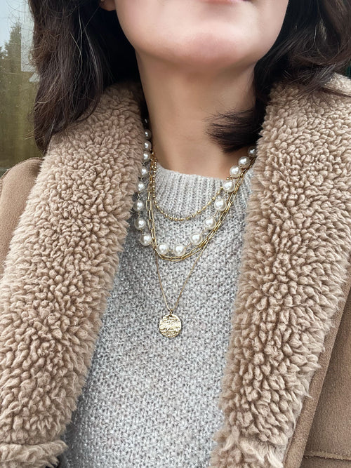 4-layer necklace featuring paperclip chain links, white pearls, gold bead accents, and a hammered coin pendant.