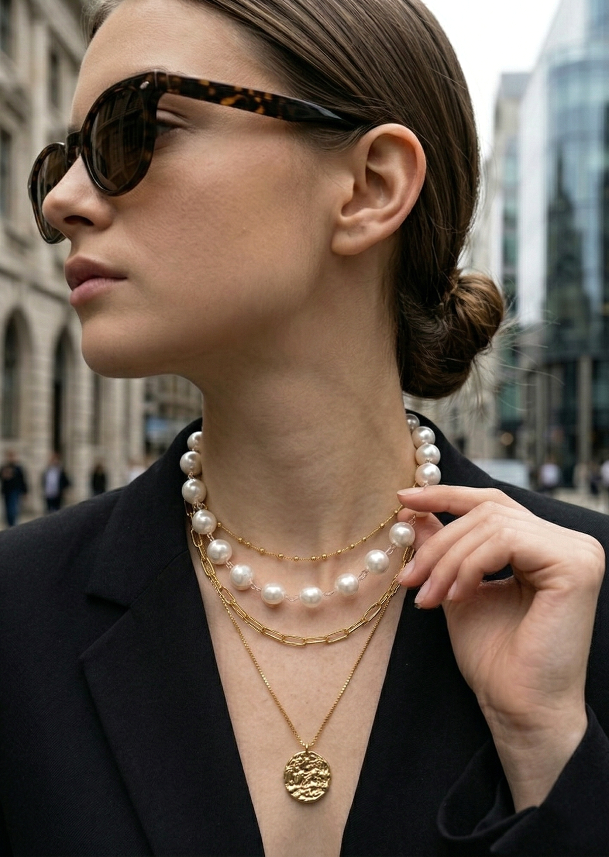 Woman wearing sunglasses and layered necklaces in an urban setting