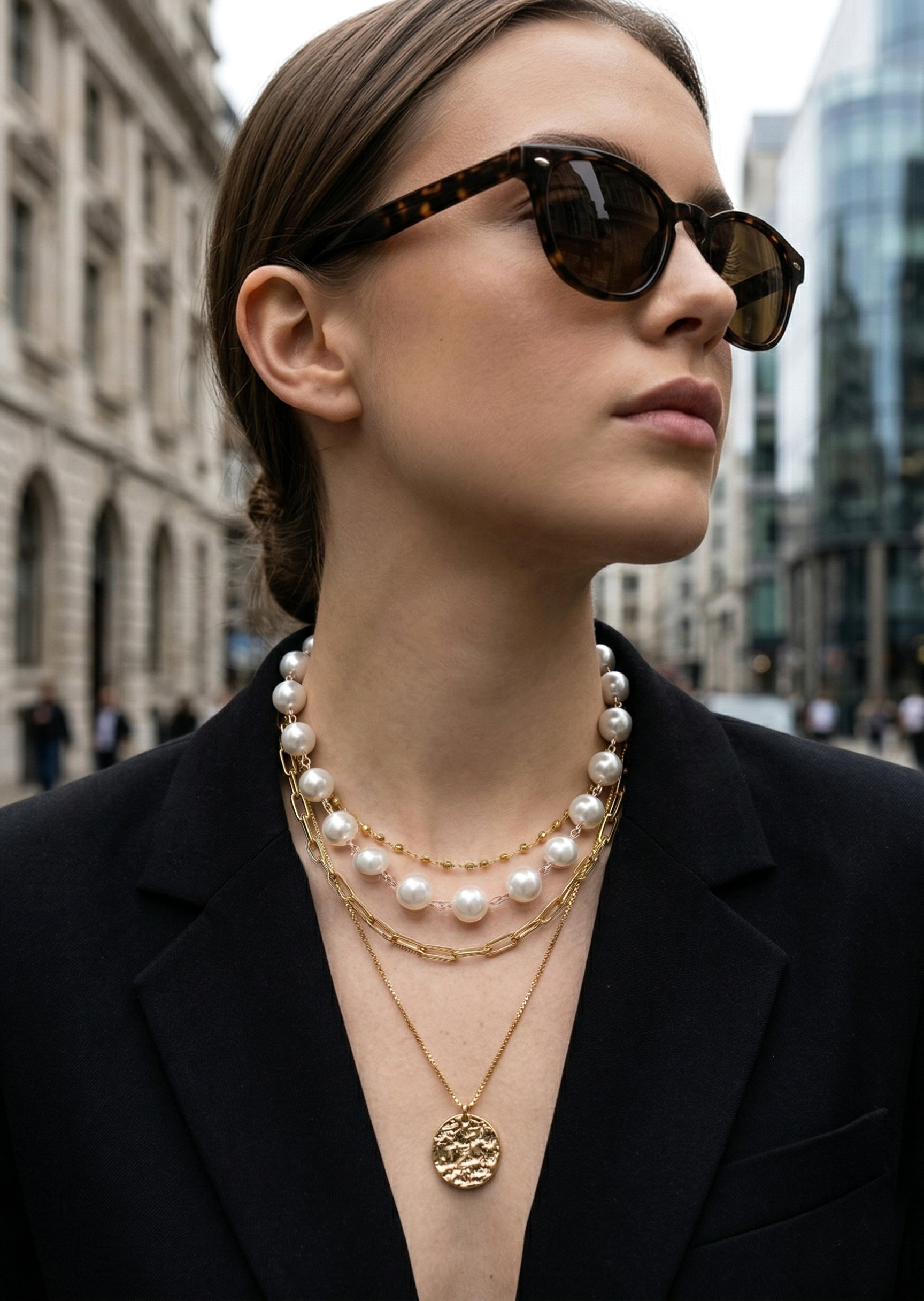 Woman wearing sunglasses and layered necklaces in an urban setting