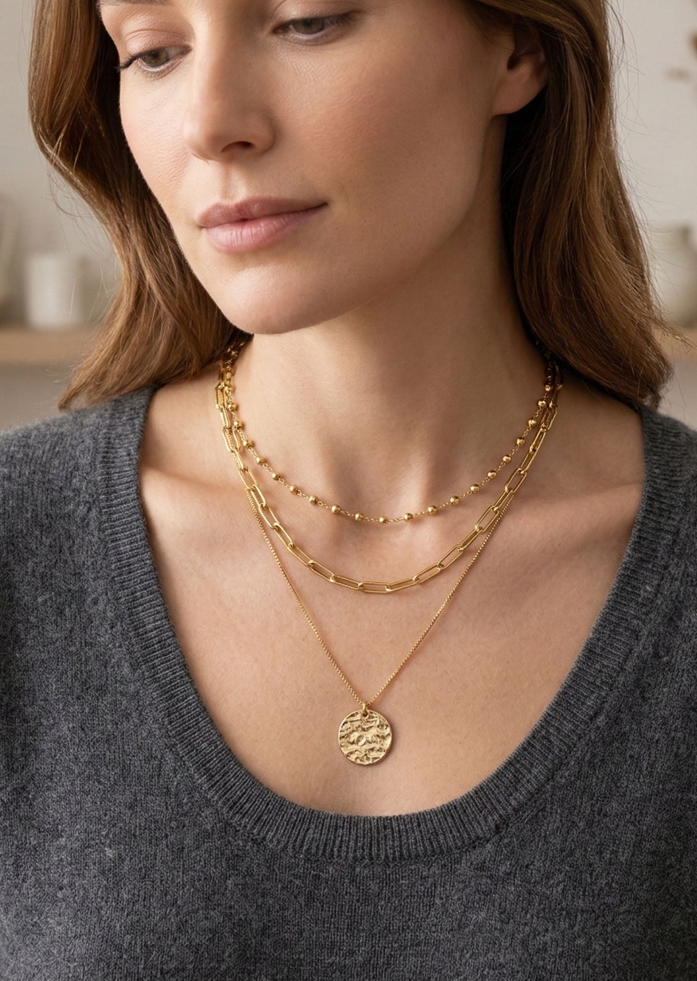 Woman wearing gold necklaces with a neutral background