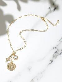 Gold necklace with charms on a marble surface