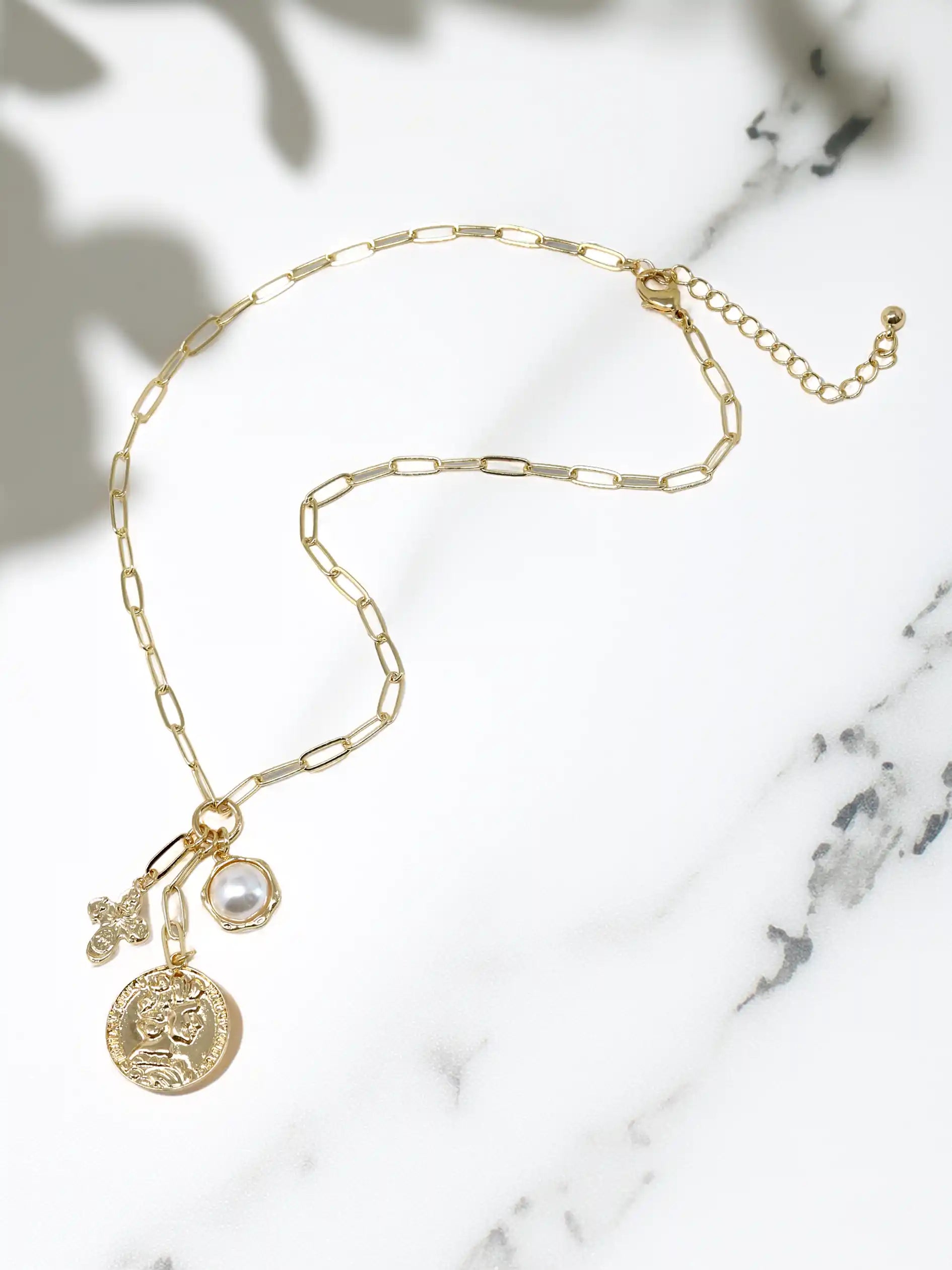 Gold necklace with charms on a marble surface