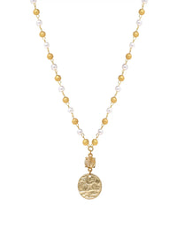A gold-tone beaded necklace featuring small round gold beads, white pearl-like beads, and a textured gold coin pendant, shown against a plain white background.