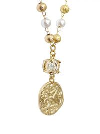A gold-toned necklace featuring textured gold beads, white pearl-like beads, a clear faceted crystal bead, and a large irregular gold pendant with an embossed floral pattern, shown on a plain white background.