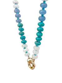 A semi-precious stone beaded necklace with faceted round beads transitioning through shades of blue, teal, green, and purple, accented by small white beads and gold-tone circle carabiner.