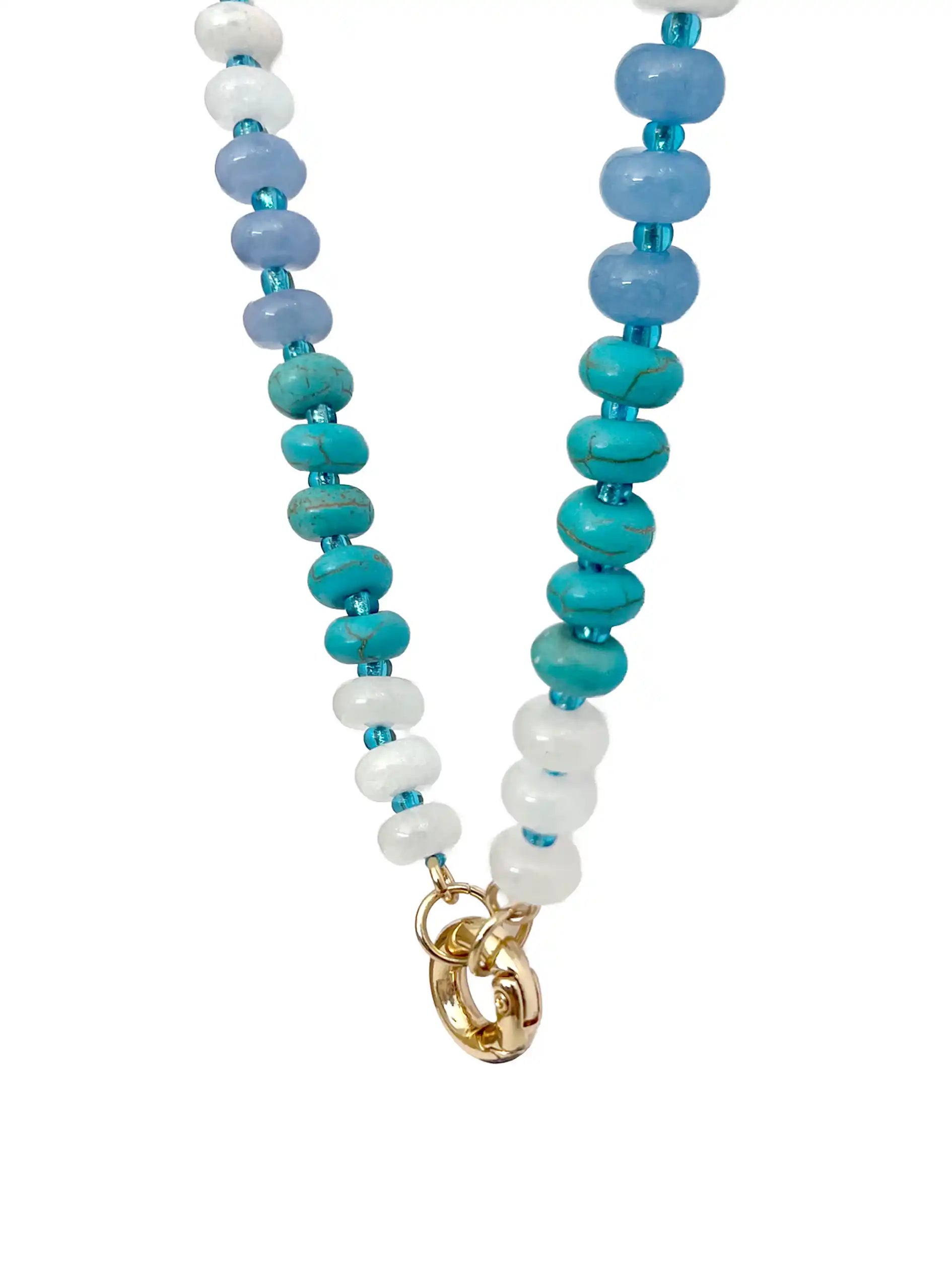 A semi-precious stone beaded necklace with faceted round beads transitioning through shades of blue, teal, green, and purple, accented by small white beads and gold-tone circle carabiner.