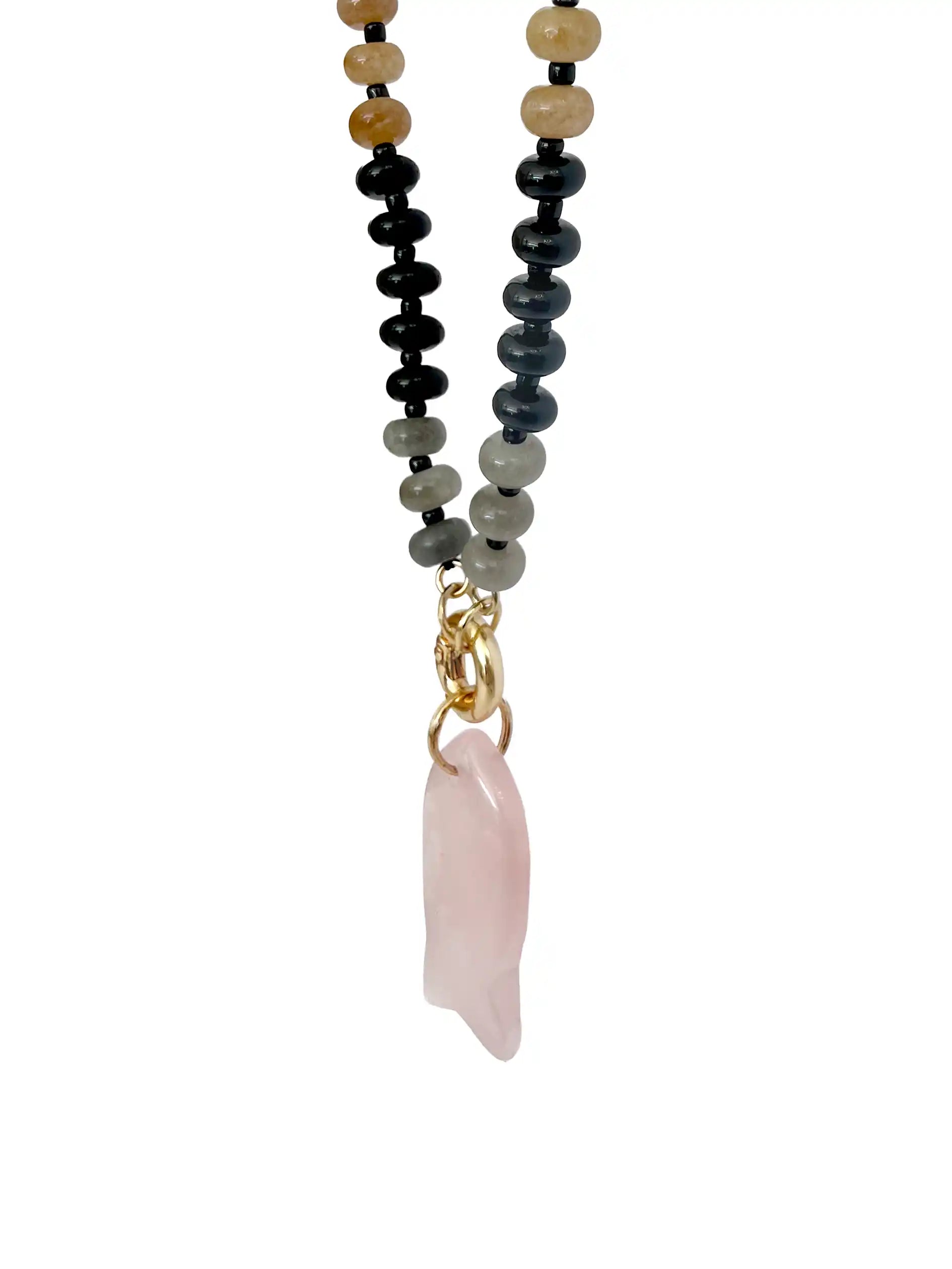 A beaded necklace featuring a dual-strand design with black and gray beads on one side, and light tan beads on the other, ending in a gold clasp and a pink rose quartz pendant, shown against a plain white background.
