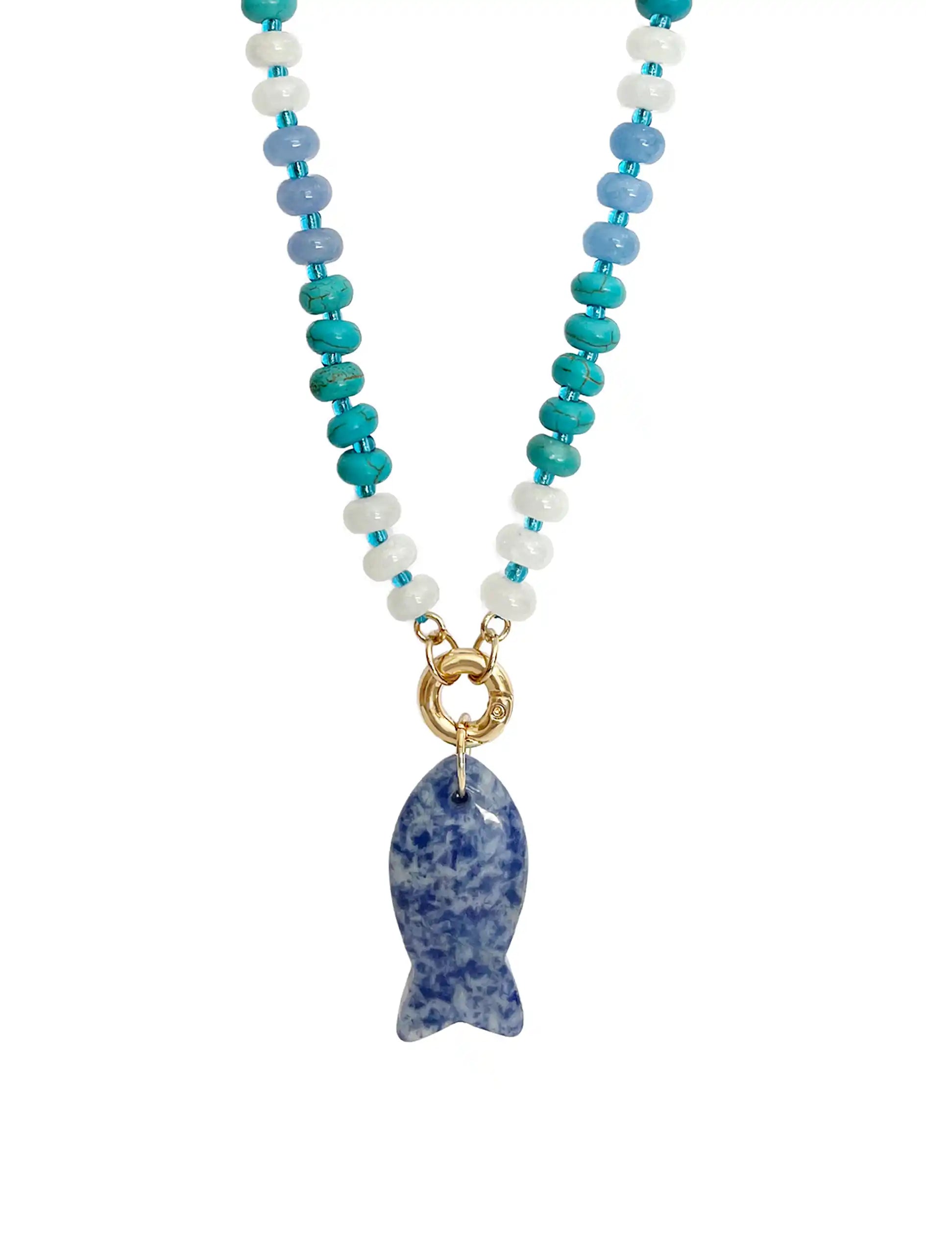 A beaded necklace featuring turquoise, light blue, and white beads with a gold-tone ring connector and a blue-and-white speckled sodalite stone fish pendant, shown against a plain white background.