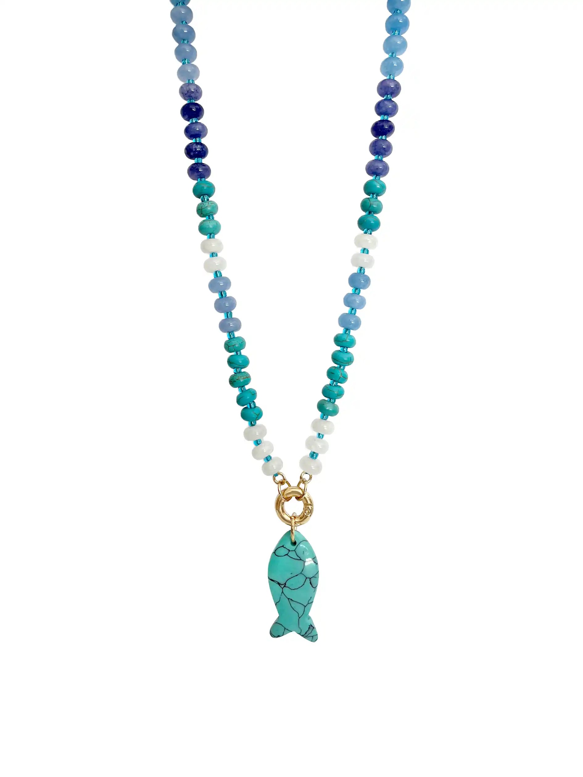 A beaded necklace featuring a gradient of blue, teal, and white beads, with a gold-tone ring clasp and a turquoise fish-shaped pendant with black veining, shown against a plain white background.