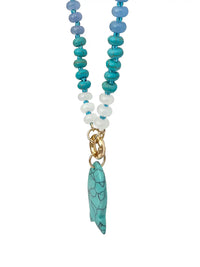 A beaded necklace featuring turquoise, light blue, and white beads with a gold-tone clasp and a turquoise stone pendant, shown against a plain white background.