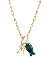 A gold paperclip chain necklace featuring a front-facing carabiner clasp that holds three distinct charms: a small round pearl, a gold script initial M, and a carved green moss agate fish pendant.