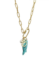 A gold paperclip chain necklace featuring a front-facing carabiner clasp that holds three distinct charms: a small round pearl, a gold script initial B, and a carved turquoise blue fish pendant.