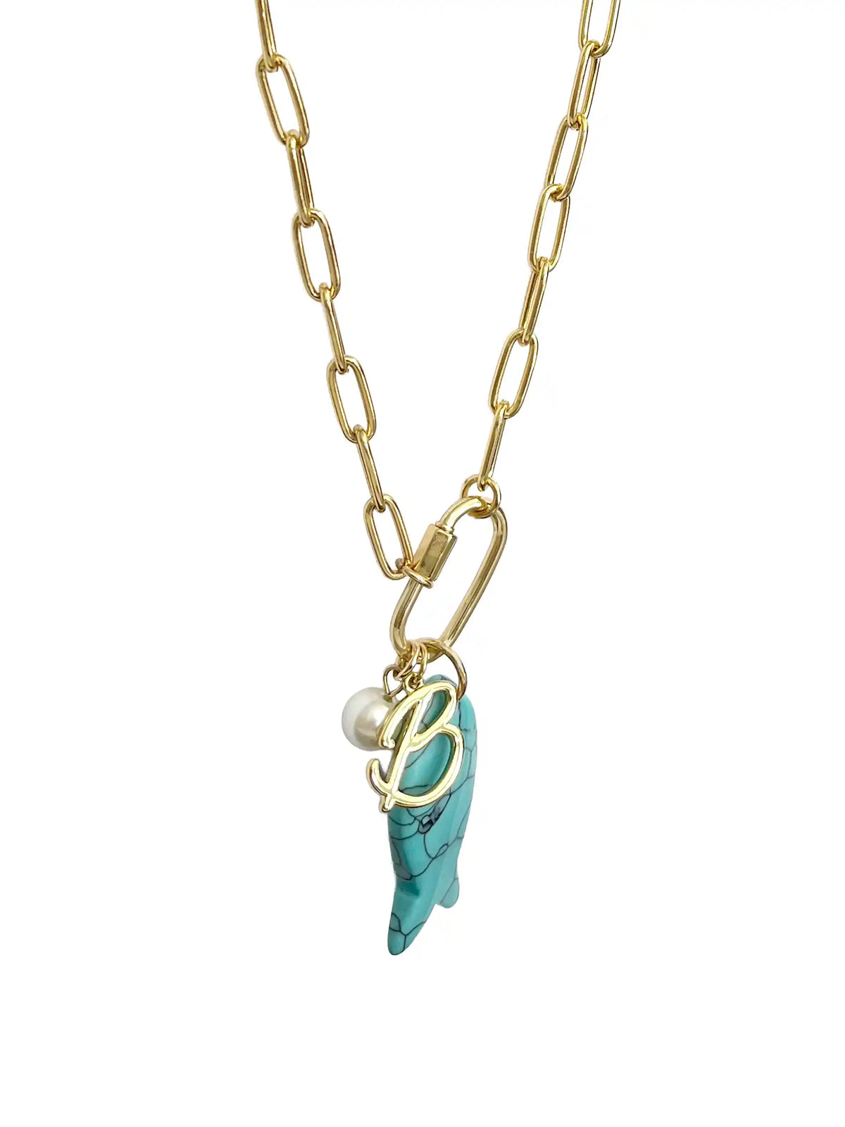A gold paperclip chain necklace featuring a front-facing carabiner clasp that holds three distinct charms: a small round pearl, a gold script initial B, and a carved turquoise blue fish pendant.