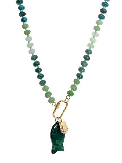 A beaded necklace featuring a gradient of green and blue stones transitioning into light mint green beads, finished with a gold carabiner holding a dark green carved fish pendant and a small gold tag.