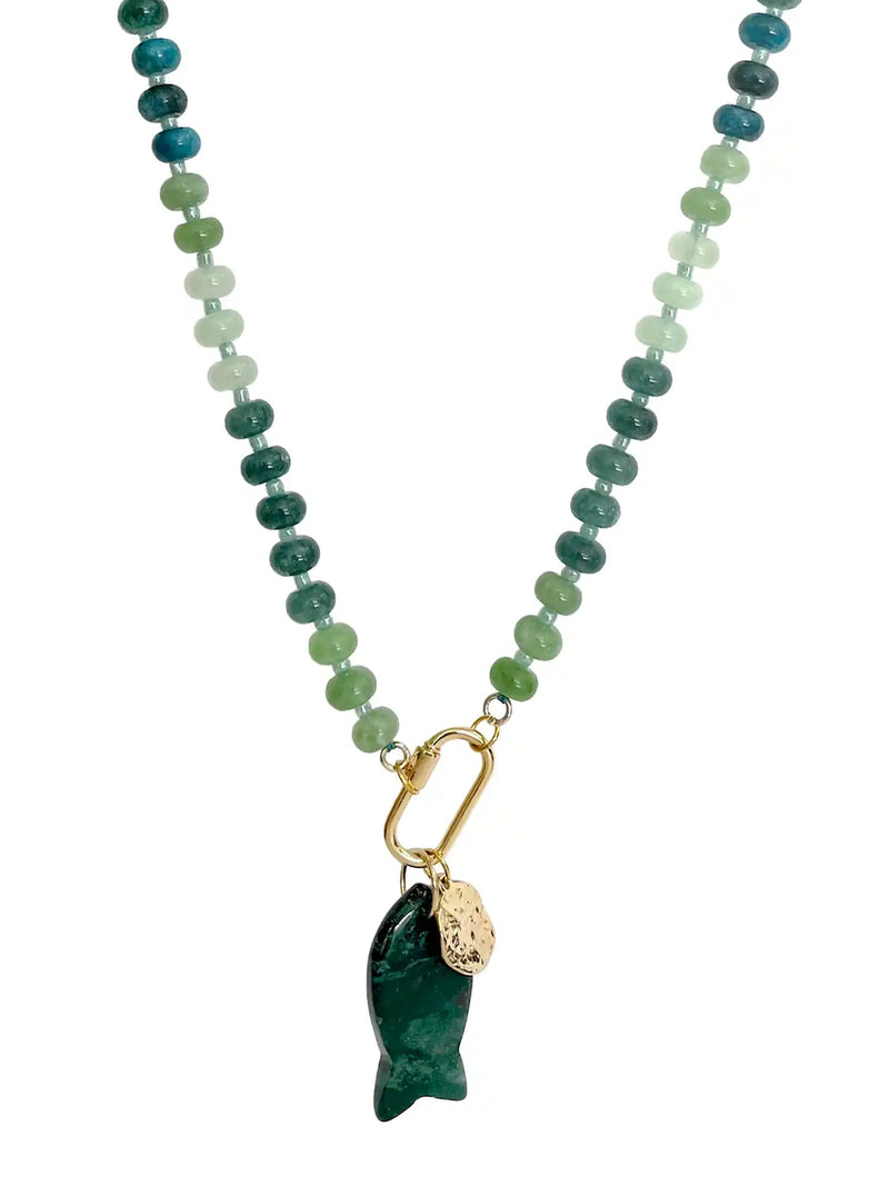 A beaded necklace featuring a gradient of green and blue stones transitioning into light mint green beads, finished with a gold carabiner holding a dark green carved fish pendant and a small gold tag.
