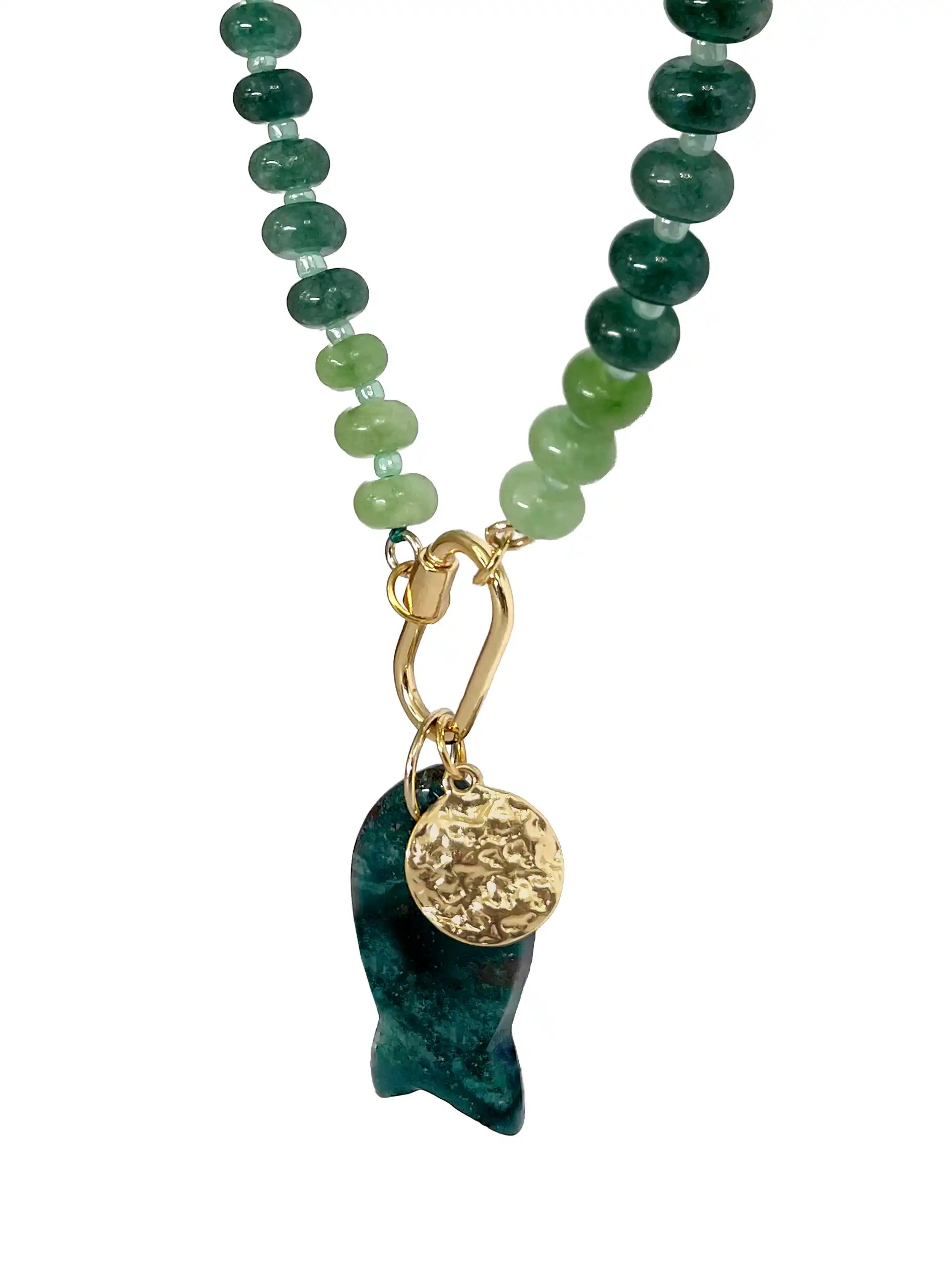 A beaded necklace featuring green and dark teal gemstone beads with a gold-tone carabiner clasp, hanging from a gold chain, and ending in a dark green stone pendant with a textured gold disc charm, shown on a plain white background.