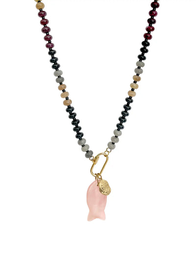 A beaded necklace featuring a strand of beads in black, gray, tan, and deep red, with a gold carabiner holding a pink rose quartz fish-shaped pendant and a small gold textured coin, shown on a plain white background.