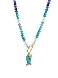 A beaded necklace featuring a gradient of blue, teal, and white beads with a gold-tone carabiner and a turquoise fish charm.