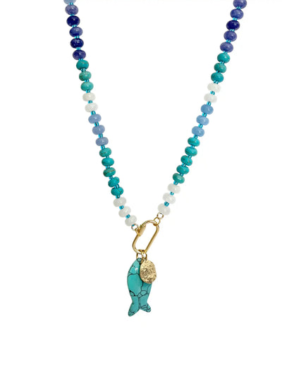 A beaded necklace featuring a gradient of blue, teal, and white beads with a gold-tone carabiner and a turquoise fish charm.
