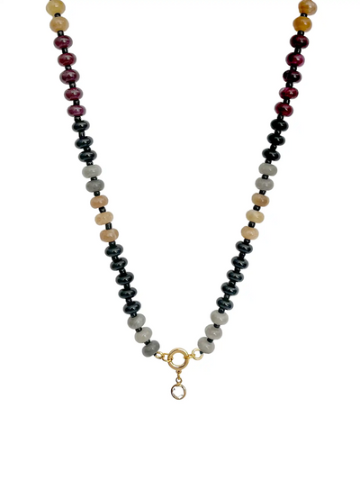 A beaded necklace featuring alternating strands of glossy black, light gray, cream, and deep burgundy beads, finished with a gold-tone ring and a small clear stone drop.