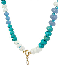 A beaded necklace featuring alternating strands of turquoise, light blue, white, and pale lavender beads, finished with a gold ring and a small dangling clear stone.