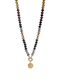 Black beaded statement necklace with mixed brown and dark red beads, gold-tone clasp, and textured round coin pendant on a white background.