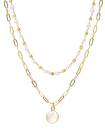 An elegant double-layered pearl and mother of pearl necklace featuring a sophisticated paperclip chain in a radiant gold finish, combining classic pearls with modern design for a timeless and stylish accessory.
