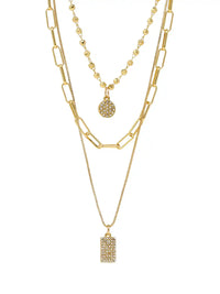 A gold layered necklace set featuring three distinct chains: a chunky paperclip chain, a delicate beaded chain with a round pavé pendant, and a fine chain with a rectangular pavé pendant, all displayed on a clean white background.