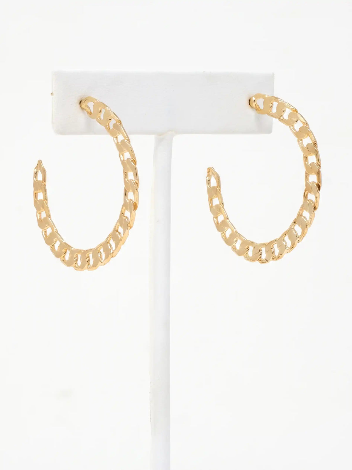 A pair of gold chain-link hoop earrings displayed on a white jewelry stand against a white background.