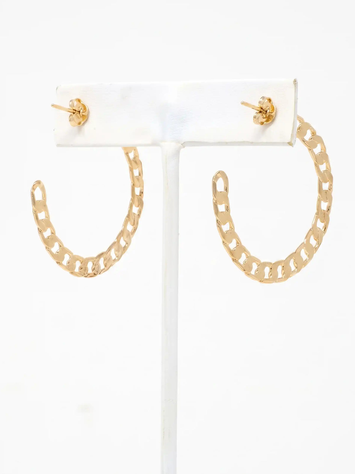 Gold chain-link hoop earrings displayed on a white T-bar jewelry stand against a plain white background.