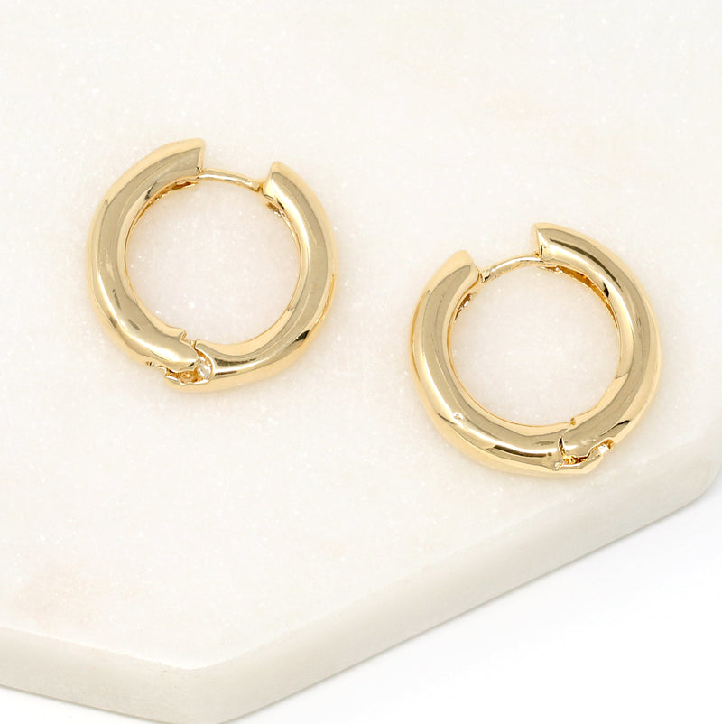 A pair of bold simple hoop huggie earrings made of gold filled.