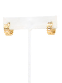 A pair of small gold hoop earrings with a textured, honeycomb-like pattern, displayed on a white T-stand against a white background.