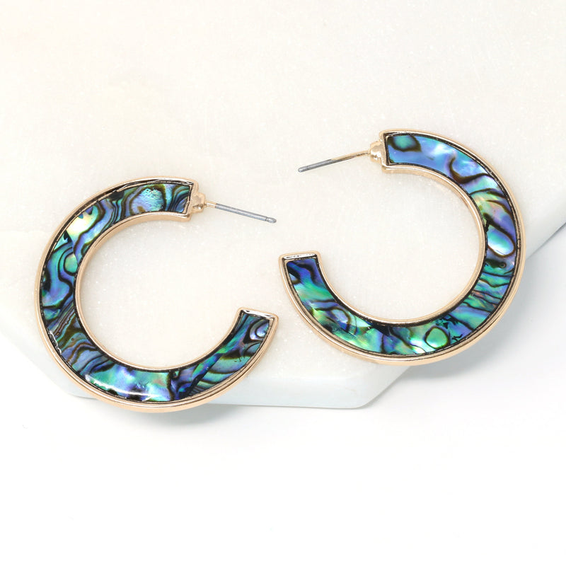 A pair of metal-mounted natural abalone shell hoop earrings. The iridescent abalone shells display beautiful shades of blue, green, black and purple, with a unique natural pattern visible from both sides. 