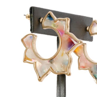 A pair of flower-shaped hoop earrings made of multicolored resin with a gold-tone outline.